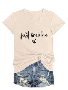 Detail of V-neck beige t-shirt with 'just breathe' print paired with denim shorts