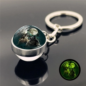 Macro shot of glow-in-the-dark wolf howling at the moon pendant on a metal keychain