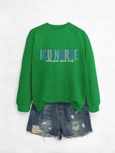Detail view of ICU Nurse crewneck sweatshirt printed on green fabric with denim shorts
