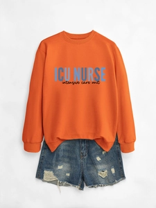 Detail of orange ICU NURSE sweatshirt paired with distressed denim shorts