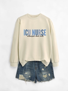 Detailed flat lay of a cream ICU NURSE sweatshirt paired with distressed denim shorts