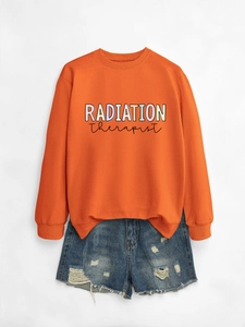 Macro shot of orange crewneck sweatshirt featuring colorful Radiation Therapist graphic print