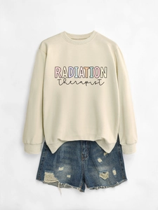 Flat lay of beige Radiation Therapist sweatshirt paired with distressed denim shorts