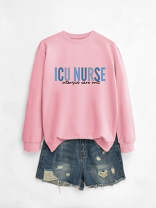 Detail of pink ICU NURSE sweatshirt paired with distressed denim shorts on gray background