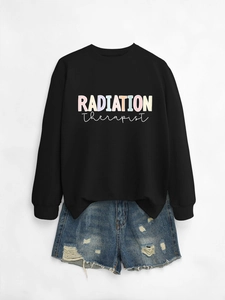 Flat lay of black radiation therapist sweatshirt paired with distressed denim shorts