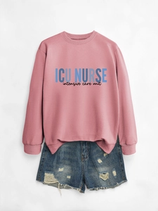 Flat lay of pink ICU NURSE crewneck sweatshirt paired with blue distressed denim shorts
