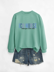 Detail of mint green sweatshirt with ICU NURSE print and distressed denim shorts