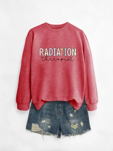 Close-up of pink Radiation Therapist crewneck sweatshirt paired with denim shorts