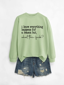 Flat lay of mint green sweatshirt with black slogan text and ripped denim shorts
