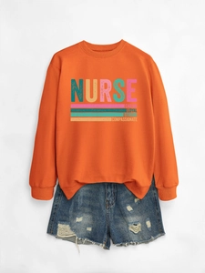 Detail of orange nurse sweatshirt with rainbow text and frayed denim shorts