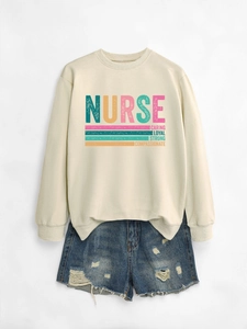 Flat lay of cream nurse sweatshirt with caring loyal strong text and denim shorts