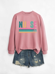 Flat lay of pink nurse sweatshirt with caring and loyal text print and denim shorts