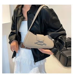 Primer plano de bolso de hombro de cuero beige con lazo decorativo y textura granulada