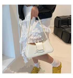 Detalle de un bolso de hombro en cuero blanco con textura de lichi y lazo elegante