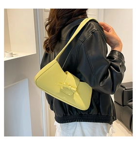 Bolso de hombro amarillo en cuero granulado con lazo sobre una chaqueta de cuero negra