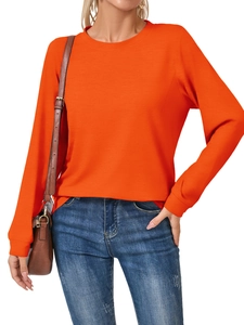 Detail of vibrant orange long sleeve crewneck sweatshirt with subtle ribbed texture fabric