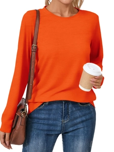 Detail of a vibrant orange long sleeve crewneck top styled with blue jeans and a brown bag
