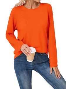 Close-up of bright orange long sleeve round neck top paired with faded denim jeans