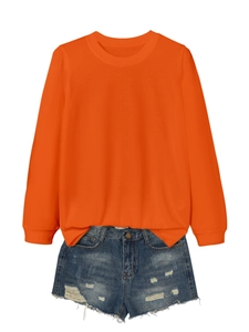 Flat lay of bright orange long sleeve sweatshirt paired with distressed denim shorts