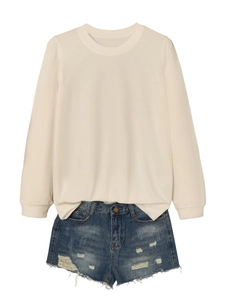 Flat lay of a beige long-sleeve sweatshirt with distressed blue denim frayed shorts