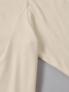 Close-up of high-quality stitching and durable knit fabric on a beige long sleeve tee