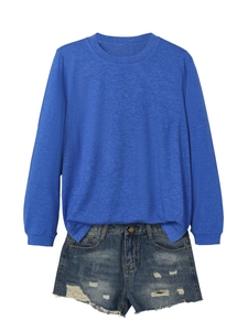 Detail of royal blue long sleeve knit top paired with distressed denim shorts on white background