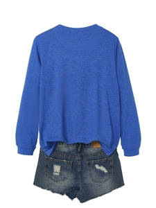 Detail of blue long sleeve knit top paired with distressed denim shorts on white background