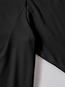 Detailed close-up of side seam stitching on high-quality black knitted long sleeve top