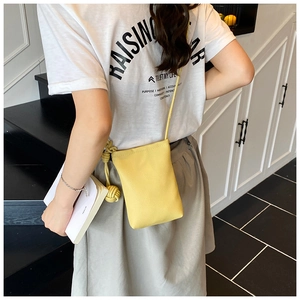Detail of yellow lychee texture phone bag with knot charm and thin round shoulder strap