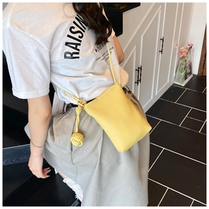 Close-up of bright yellow lychee leather texture and knotted cotton rope strap of mobile bag