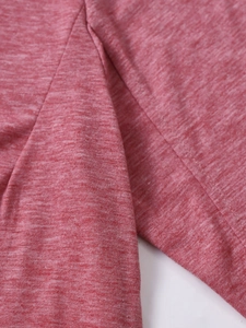 Detail of soft heathered red knit fabric with durable overlock stitching on the sleeve