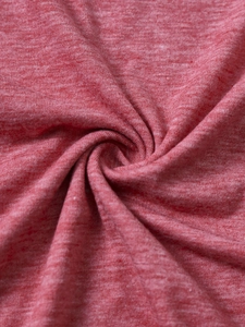 Macro shot of heather red knit fabric texture showing spiral folds and soft stitch detail
