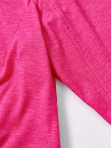 Detailed macro view of high-quality heather rose red knit fabric and neat side seams