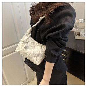 Détail d'un sac sous le bras blanc avec broderie florale et texture dentelle sur modèle