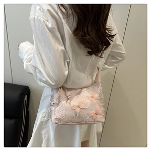 Détail du sac à épaule en dentelle rose avec broderie papillon 3D sur un mannequin