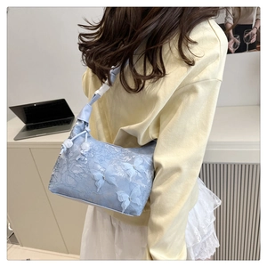 Détail du sac à bandoulière en dentelle bleu clair avec papillons 3D sur le modèle