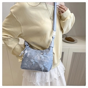Détail du sac bandoulière en dentelle bleu clair avec papillons 3D et perles décoratives