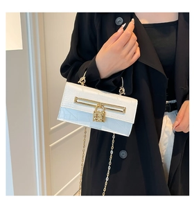 Detail of white crocodile embossed leather handbag with gold metal lock and handle