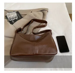 Comparaison de taille d'un sac hobo en cuir marron à côté d'un smartphone et dimensions
