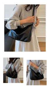 Vue détaillée de la texture du cuir noir souple et de la large bandoulière de ce sac à main