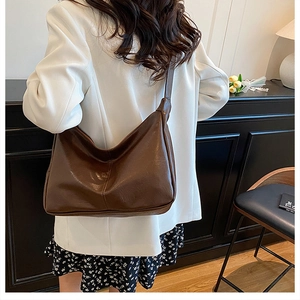 Grand sac cabas en cuir marron foncé porté par un mannequin dans un cadre de bureau chic
