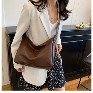 Detailed view of dark brown faux leather shoulder bag with wide strap and soft texture