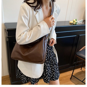 Brown leather crossbody dumpling bag shown on a model in a stylish indoor setting
