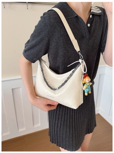 Detail of off-white shoulder bag with decorative chain and cute character charm on the side