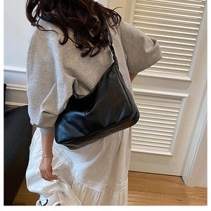 Détail d'un grand sac hobo noir en similicuir à texture huilée pour le quotidien