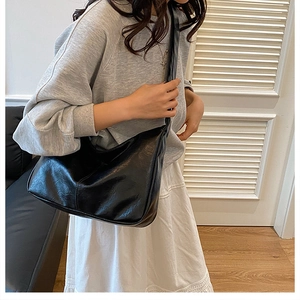 Détail d'un grand sac hobo en cuir PU noir avec bandoulière large porté par un mannequin