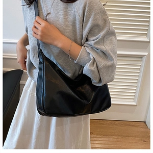 Side view of a large black half-moon crossbody bag shown on model with wide strap detail