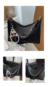 Detail of black crescent shoulder bag with metallic chain and pearl doll charm