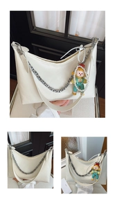 Detail of off-white shoulder bag featuring silver hollow chain and decorative pendant