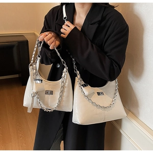 Close-up of white glossy patent leather bag with silver chain and mini pouch detail